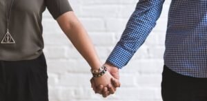 Pareja tomada de las manos. Ella lleva collar de Harry Potter